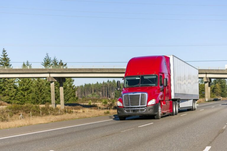 tractor trailer on highway with overpass in the background